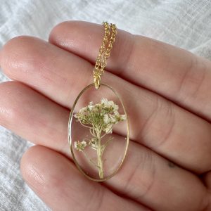 Large Gold Oval Necklace With A Bunch Of White Flowers